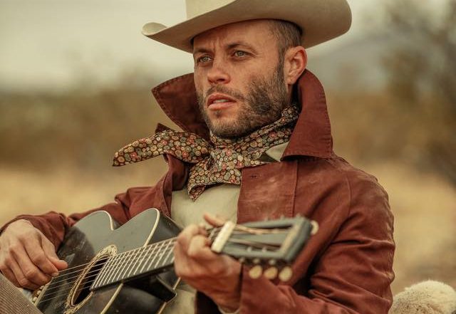 Charley crockett playing guitar outside